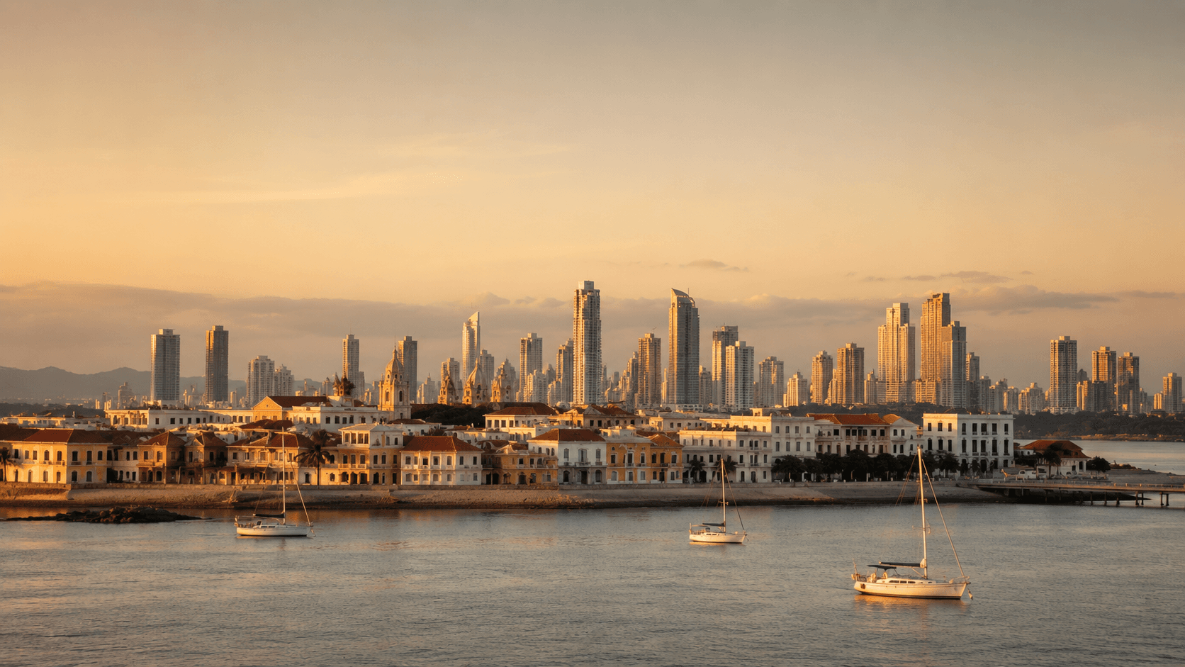The skyline of Panama City seen across the water at golden hour — modern towers behind the low pastel rooftops and church spires of the Casco Viejo old quarter, with the Pacific in the foreground. No people, no readable signage. The image pairs Panama's modern, dollarized stability with its colonial charm, the two things that make its Pensionado one of the most recommended retirement visas in the world.