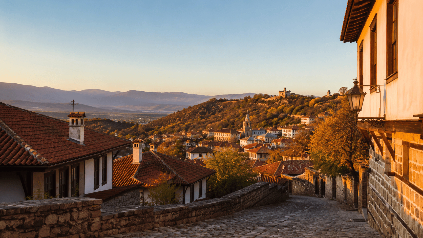 Plovdiv, Bulgaria or Veliko Tarnovo at golden hour — Ottoman-era cobblestone streets and terracotta-roofed buildings on a hillside, distant Rhodope mountains, late-afternoon light. The image represents the Eastern European cluster of countries the cost-of-living data flags as affordable on $1,500/month but where retirement-visa pathways are largely absent.